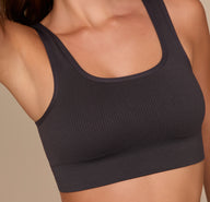 Close-up shot of the Lounge Rib Scoop Bralette in Charcoal, worn by Alexis, showing the fine rib knit fabric and clean neckline finishing for a soft, barely-there feel.