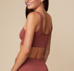 Anna is shown from the side, displaying the back view of the Lounge Rib Scoop Bralette and Lounge Rib Boyshort in Clay.