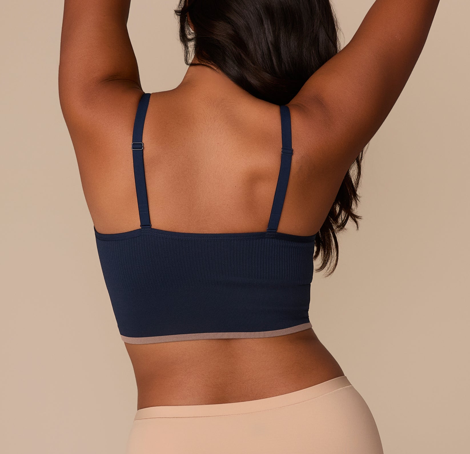 Rear view of Victoria in the Lounge Rib Triangle Bralette in True Blue. The slim adjustable straps connect to a straight-cut back panel, allowing for a secure and comfortable fit across the shoulders. The ribbed texture and contrast hem detail continue around the back.