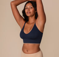 Victoria modeling the Lounge Rib Triangle Bralette in True Blue from a side angle with her arms raised, showcasing the supportive yet flexible fit of the ribbed fabric and the flattering low-cut neckline.