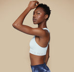 Side profile of model Mariah in the Move Sports Bra in Ice, with one hand resting on her head, emphasizing the comfortable fit and supportive design.