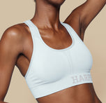 Close-up side view of Mariah wearing the Move Sports Bra in Ice, highlighting the scoop neckline and Harper Wilde logo on the band.