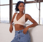 Ally wearing the Bliss Plunge Adjustable Bralette in Rose, styled with jeans in a casual leaning against a bright window.