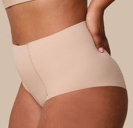 A close-up of India gently resting her hand on her hip while wearing the No-Show Highwaist Brief in Beige, showcasing the soft, elastic-free waistband.