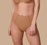 A close-up of Gracie wearing the No-Show Highwaist Brief in Tan. The seamless, high-waisted design offers a smooth, invisible fit under clothing. sizing: Gracie wears size Small
