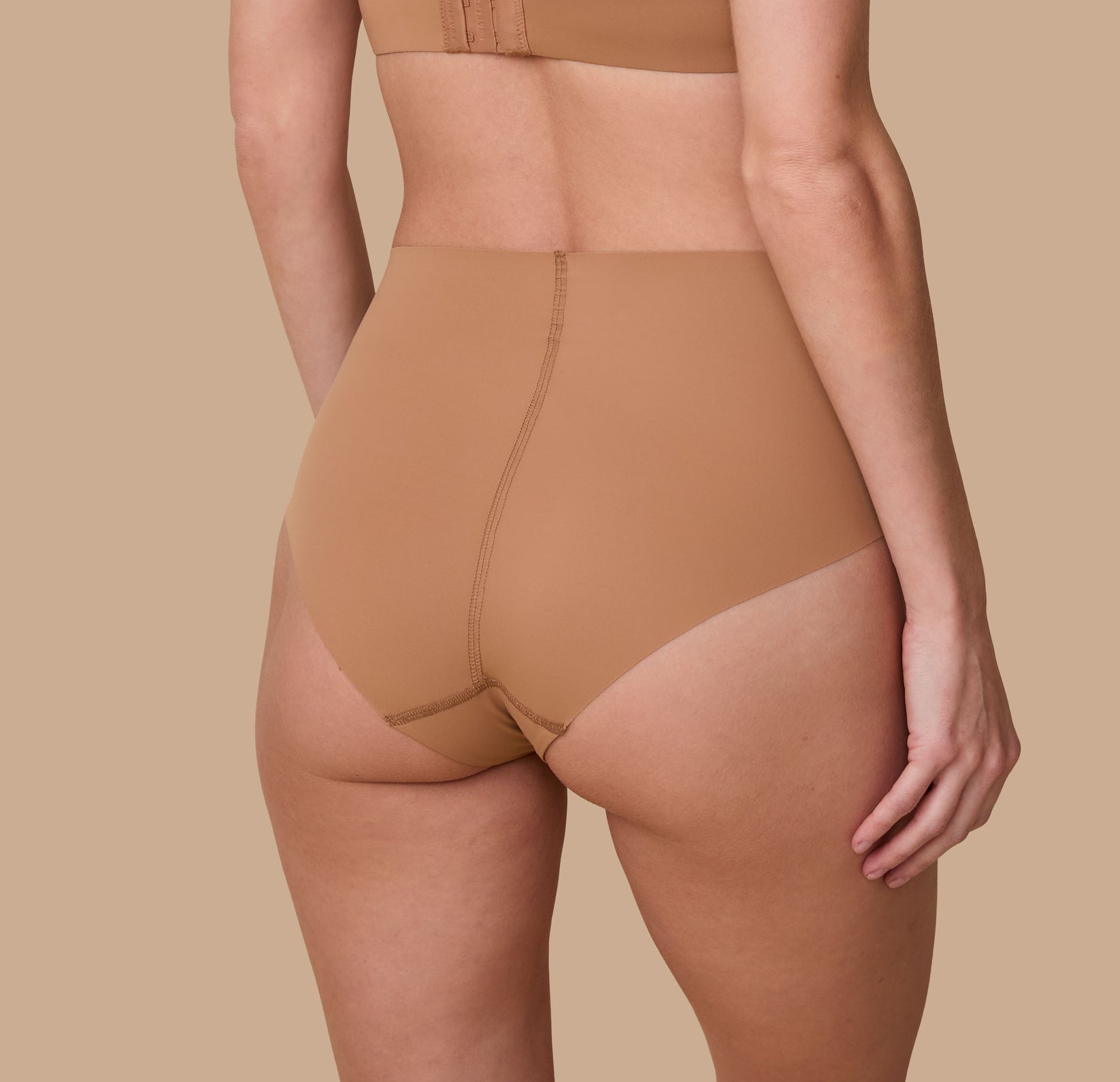 Gracie is shown from behind, highlighting the brief’s full-coverage back and raw-cut edges that lay flat for a no-show look.
