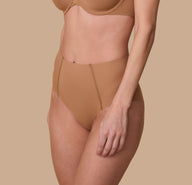 A three quarter profile of Gracie in the No-Show Highwaist Brief in Tan, emphasizing the soft, seamless waistband and smoothing fabric.