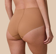 Gracie is shown from behind in a detailed, up-close shot, highlighting the brief’s full-coverage back and raw-cut edges that lay flat for a no-show look.