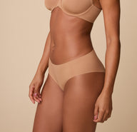 A three quarter profile of Ally in the No-Show Hiphugger in Tan, emphasizing the soft, elastic-free waistband and invisible fit.