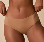 Ally gently pulls the waistband of the No-Show Hiphugger in Tan, demonstrating the soft, flexible fit.