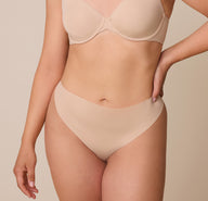 A detailed shot of the No-Show Thong in Beige on Emersyn, focusing on the barely-there waistband that lays smooth on the skin. sizing: Emersyn wears size Large