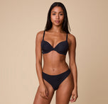 Ally wearing the No-Show Thong in Black paired with a matching Base T-Shirt Bra, standing against a neutral backdrop.