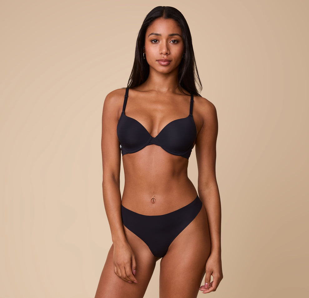 Ally wearing the No-Show Thong in Black paired with a matching Base T-Shirt Bra, standing against a neutral backdrop.