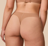 A detailed close-up of the back of the No-Show Thong in Tan, focusing on how the fabric molds to Emersyn's body. 