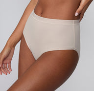 On a light gray studio backdrop, Courtney wears the Bliss Highwaist Brief in Pebble, shown in a three-quarter side view highlighting the high-rise waist, smooth microfiber fabric, and clean side seam.