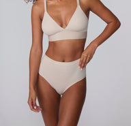 On a light gray studio backdrop, Courtney wears the Bliss Highwaist Brief in Pebble with the matching Bliss Triangle Bralette, shown in a full front view highlighting the high-rise waist, smooth microfiber fabric, and clean, no-show edges.