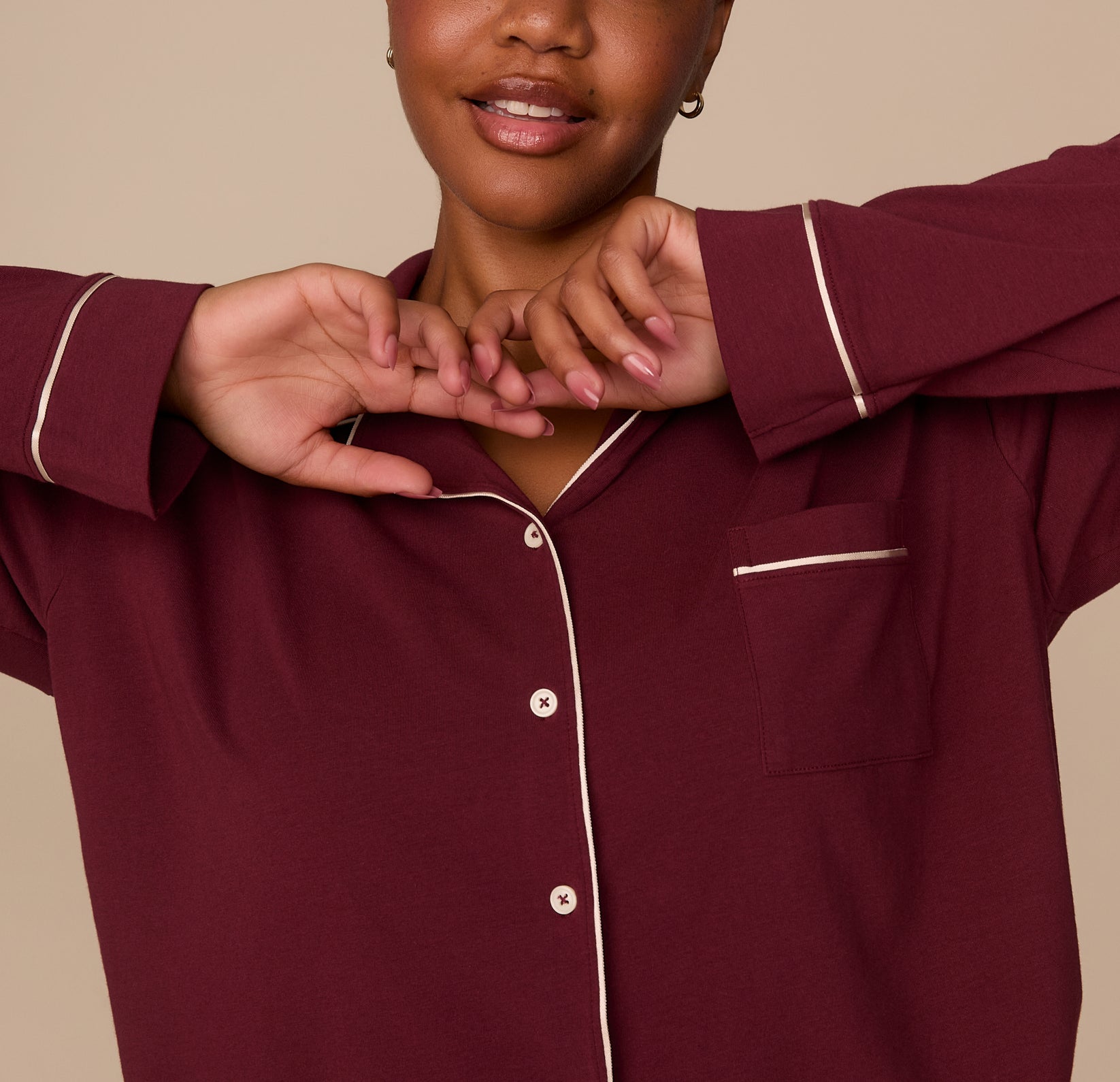 Partial close-up of model Zarria wearing the Perfect Pima Long Sleeve Pajama Shirt in Bordeaux. Her arms are raised near her face, showing the sleeve and front button detail.