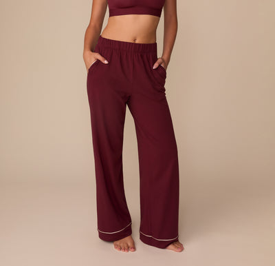 Front view of model Alexis wearing the Perfect Pima Pajama Pants in Bordeaux. The pants have a relaxed, wide-leg silhouette with contrast piping at the hem and an elastic waistband. sizing: Alexis wears size Small