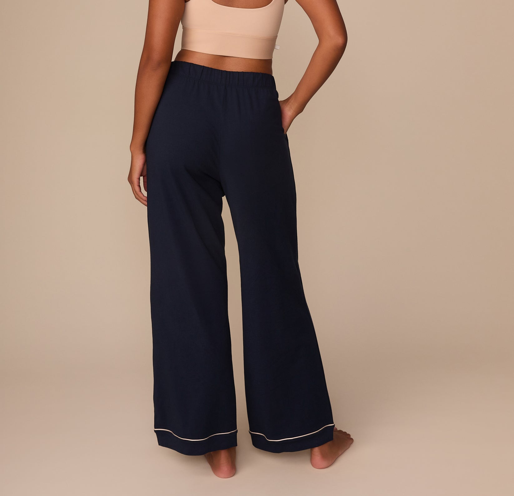 Rear view of the pajama pants showing the back elastic waistband and the drape of the wide-leg design, with Victoria standing in a relaxed pose.