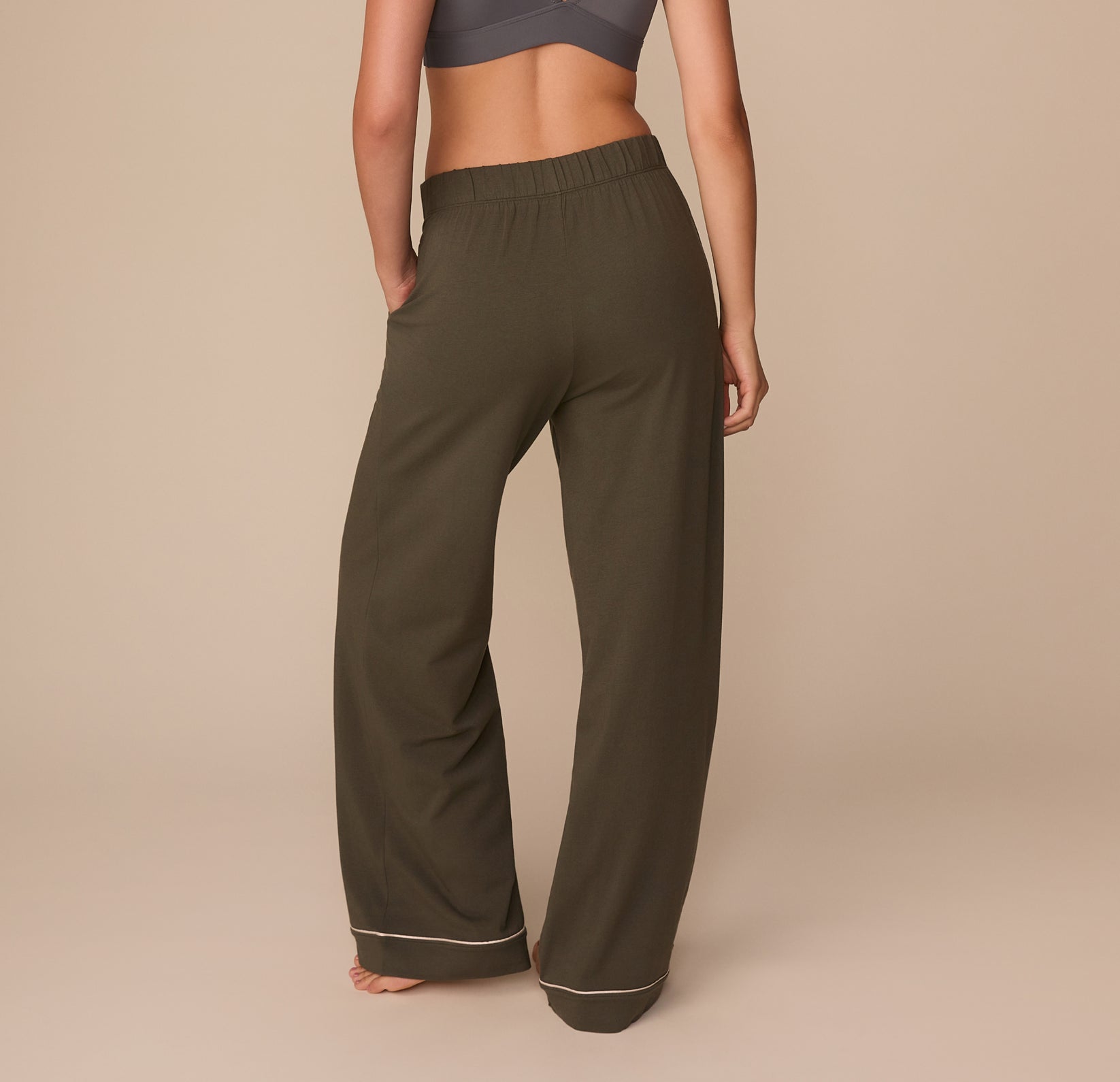 Back view of Alexis in the Perfect Pima Pajama Pants in Olive. The image highlights the elastic waistband and soft drape of the wide-leg silhouette, finished with contrast piping.
