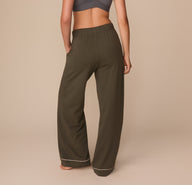 Back view of Alexis in the Perfect Pima Pajama Pants in Olive. The image highlights the elastic waistband and soft drape of the wide-leg silhouette, finished with contrast piping.