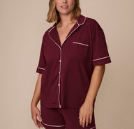 Front view of model Sonnie wearing the Perfect Pima Pajama Shirt and Shorts in Bordeaux. The button-down shirt features white contrast piping along the collar, sleeves, and chest pocket. sizing: Sonnie wears size Large