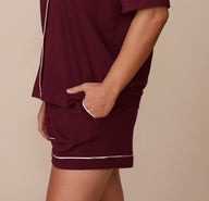 Side view of model Sonnie wearing the Perfect Pima Pajama Shirt and Shorts set in Bordeaux, with one hand tucked into the shorts pocket.
