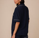 Back view of Marcela in the Perfect Pima Pajama Shirt in Navy, showing the loose drape and white piping detail across the upper back and sleeve hems.