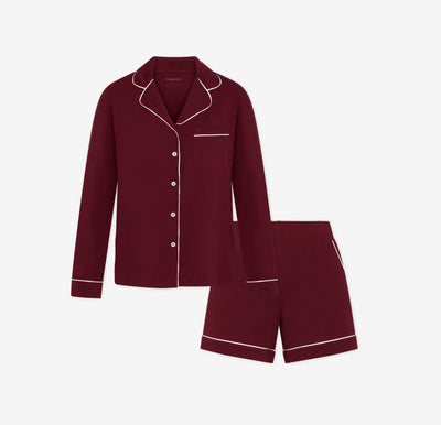 Harper Wilde Pima Pajama Set in Bordeaux. Includes long sleeve button down with white chest pocket piping and matching pajama shorts. Set laid flat on a white background.