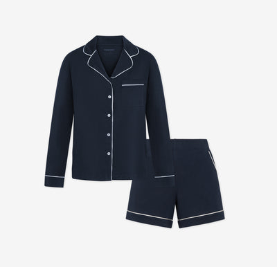 Harper Wilde Pima Pajama Set in Navy. Includes long sleeve, button-up top with white piping and matching pajama shorts. Set laid flat on a white background.