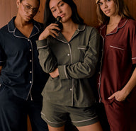 Three women dressed in Pima cotton sleep sets—navy, olive, and bordeaux—styled with short or long sleeves and shorts or pants, standing casually in coordinated looks.
