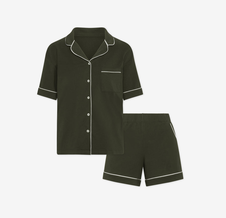 Harper Wilde Pima Pajama Set in Olive. Includes short sleeve, button-up top with white piping and matching pajama shorts. Set laid flat on a white background.
