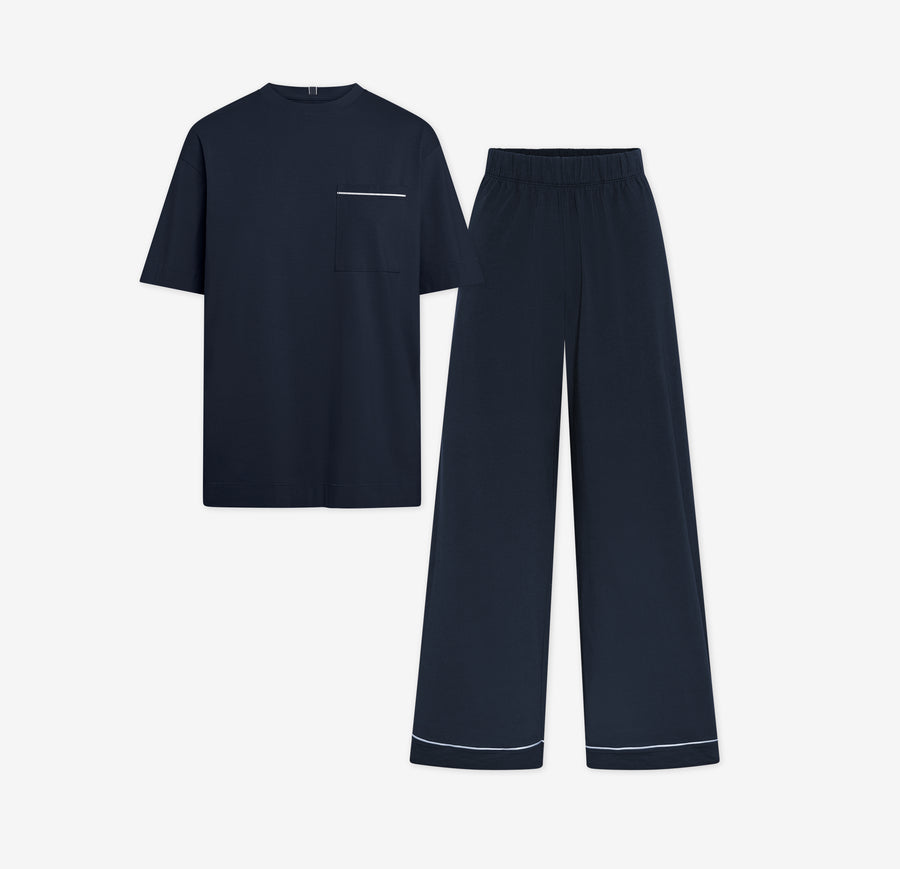 Harper Wilde Pima Pajama Set in Navy. Includes relaxed fit tee with white chest pocket piping and matching long pants. Set laid flat on a white background.