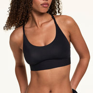 Front view of model wearing the Bliss Racerback Bralette in Black, showing the scoop neckline and adjustable racerback straps.