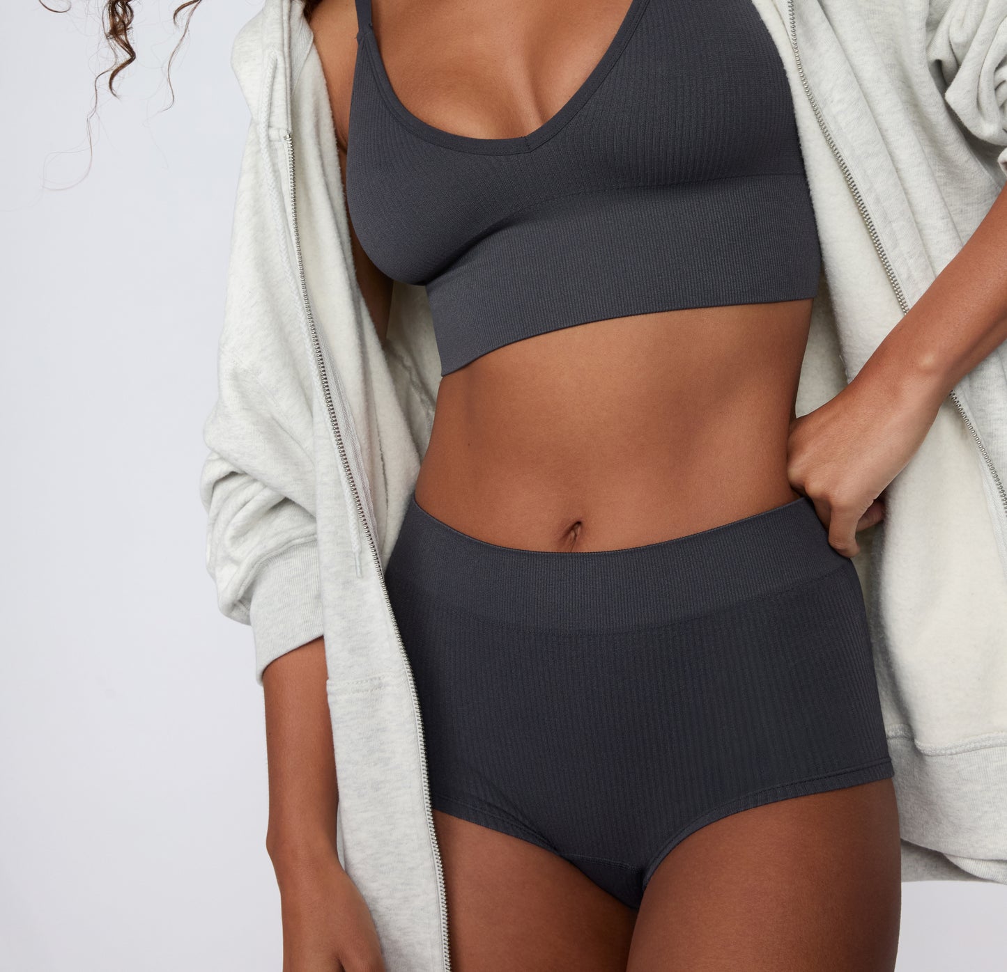 On a clean studio backdrop, a model wears the Ribbed Boyshort in Charcoal, shown from the front with a wide, ribbed waistband and soft, stretchy fabric.
