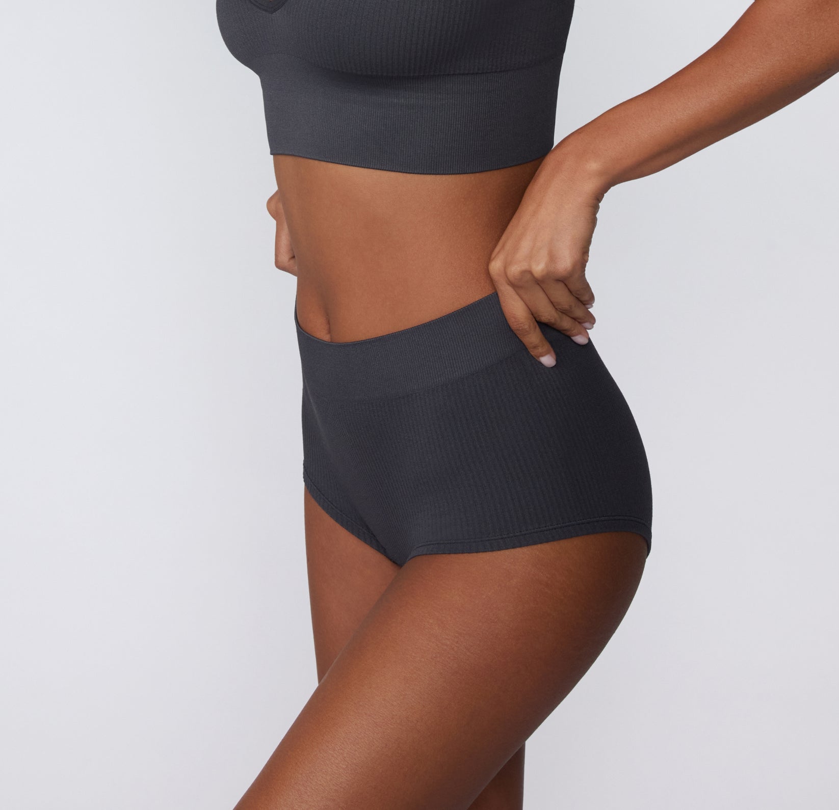 Side view of a model wearing the Ribbed Boyshort in Charcoal, highlighting the smooth leg opening and ribbed texture.