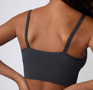 On a light studio backdrop, a close-up angled view shows a model wearing the Ribbed Triangle Bralette in Charcoal, focusing on the ribbed texture, triangle shape, and soft stretch.