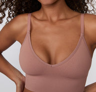 On a light studio backdrop, a close-up front view shows a model wearing the Ribbed Triangle Bralette in Plum, focusing on the triangle shape, soft ribbed texture, and thin straps.