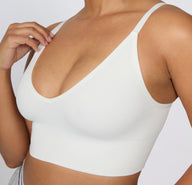 On a light studio backdrop, a close-up front view shows a model wearing the Ribbed Triangle Bralette in White, focusing on the triangle shape, ribbed fabric, and smooth underband.