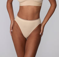On a light gray studio backdrop, a front close-up of Courtney wearing the Smooth Seamless underwear in Beige shows the soft, stretchy microfiber fabric and flat waistband designed to sit smoothly.