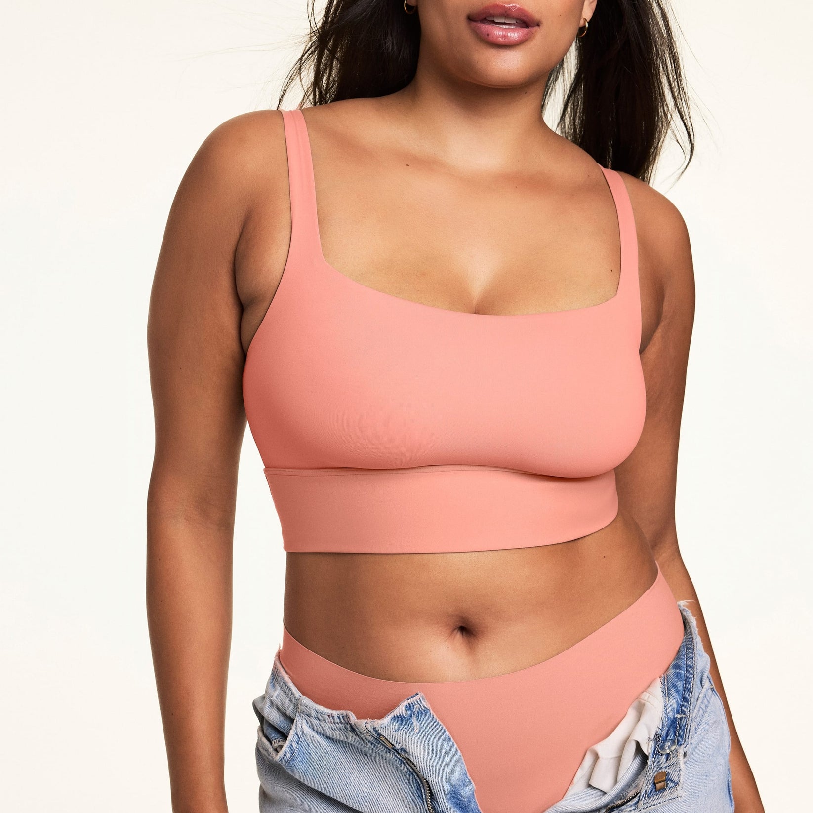 Front view of model wearing the Bliss Squareneck Bralette and matching high-waist underwear in Cabana, with unfastened light wash denim jeans.