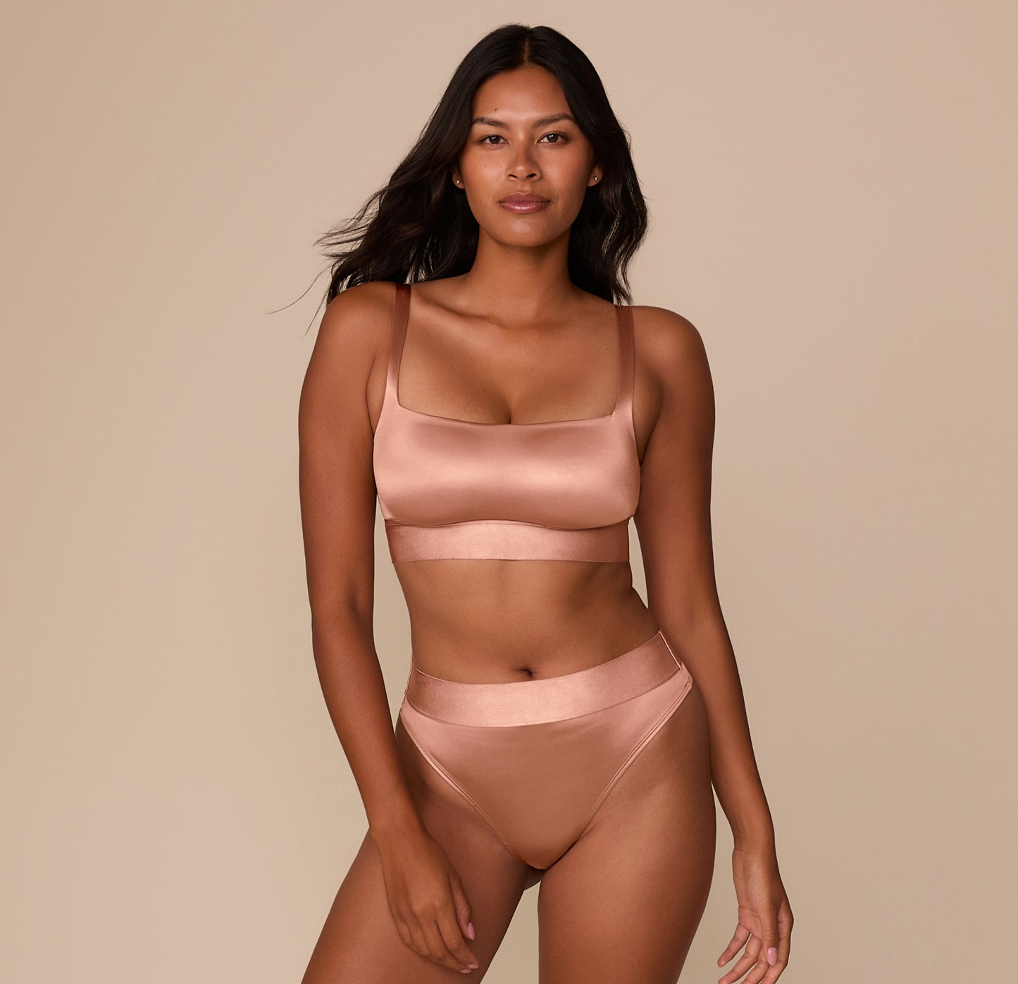 Full body shot of Victoria pairing the Stretch Satin Square Neck Bralette in Champagne with matching Stretch Satin Highwaist Thong. Her hands are relaxed at her sides, showcasing the full longline cut.