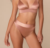 Alexis wearing the Stretch Satin Highwaist Thong in Champagne. The image shows a front view highlighting the wide waistband and smooth, satiny finish. sizing: Alexis wears size Small