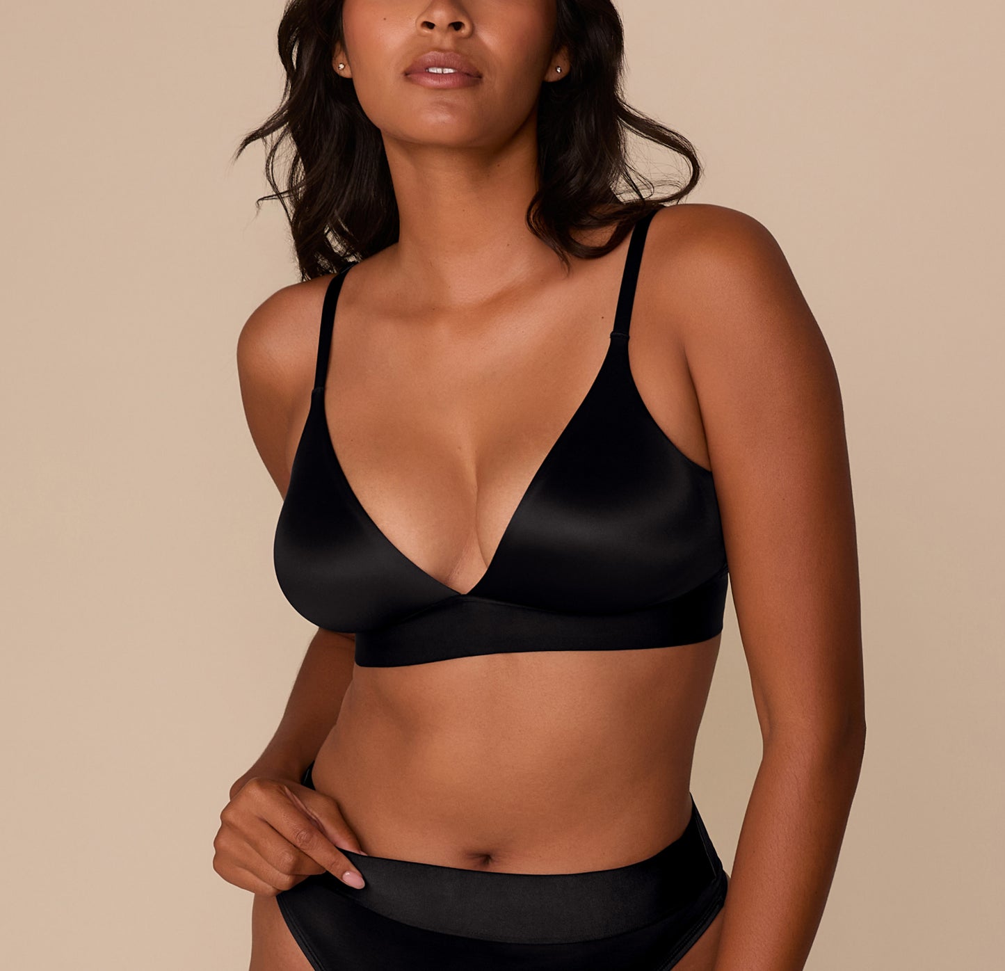 Victoria wearing the Stretch Satin Triangle Bralette in Black. The image is a front view showing the deep V neckline and smooth, satiny finish of the wireless cups. sizing: Victoria wears size Medium