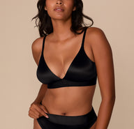 Victoria wearing the Stretch Satin Triangle Bralette in Black. The image is a front view showing the deep V neckline and smooth, satiny finish of the wireless cups. sizing: Victoria wears size Medium