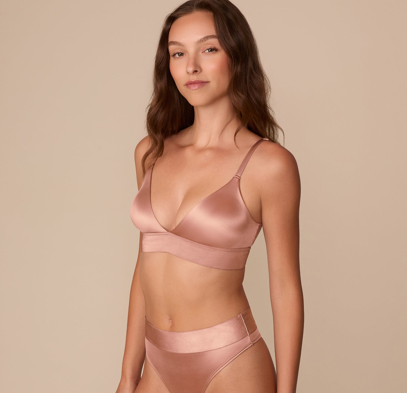 Side view of Alexis in the Stretch Satin Triangle Bralette and coordinating Stretch Satin Highwaist Thong in Champagne. The triangle shape and subtle sheen of the fabric are visible.