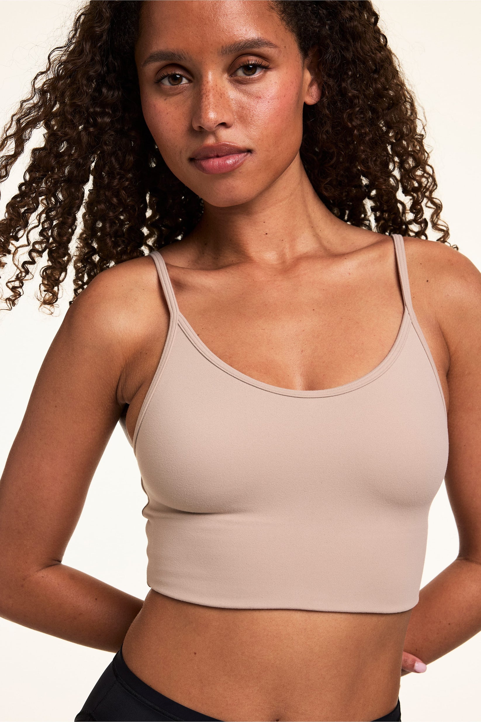 On a light studio backdrop, Courtney wears the Whipped Knit Scoop Bralette in Mushroom with black underwear. The longline bralette features a scoop neckline, slim straps, and smooth knit construction.