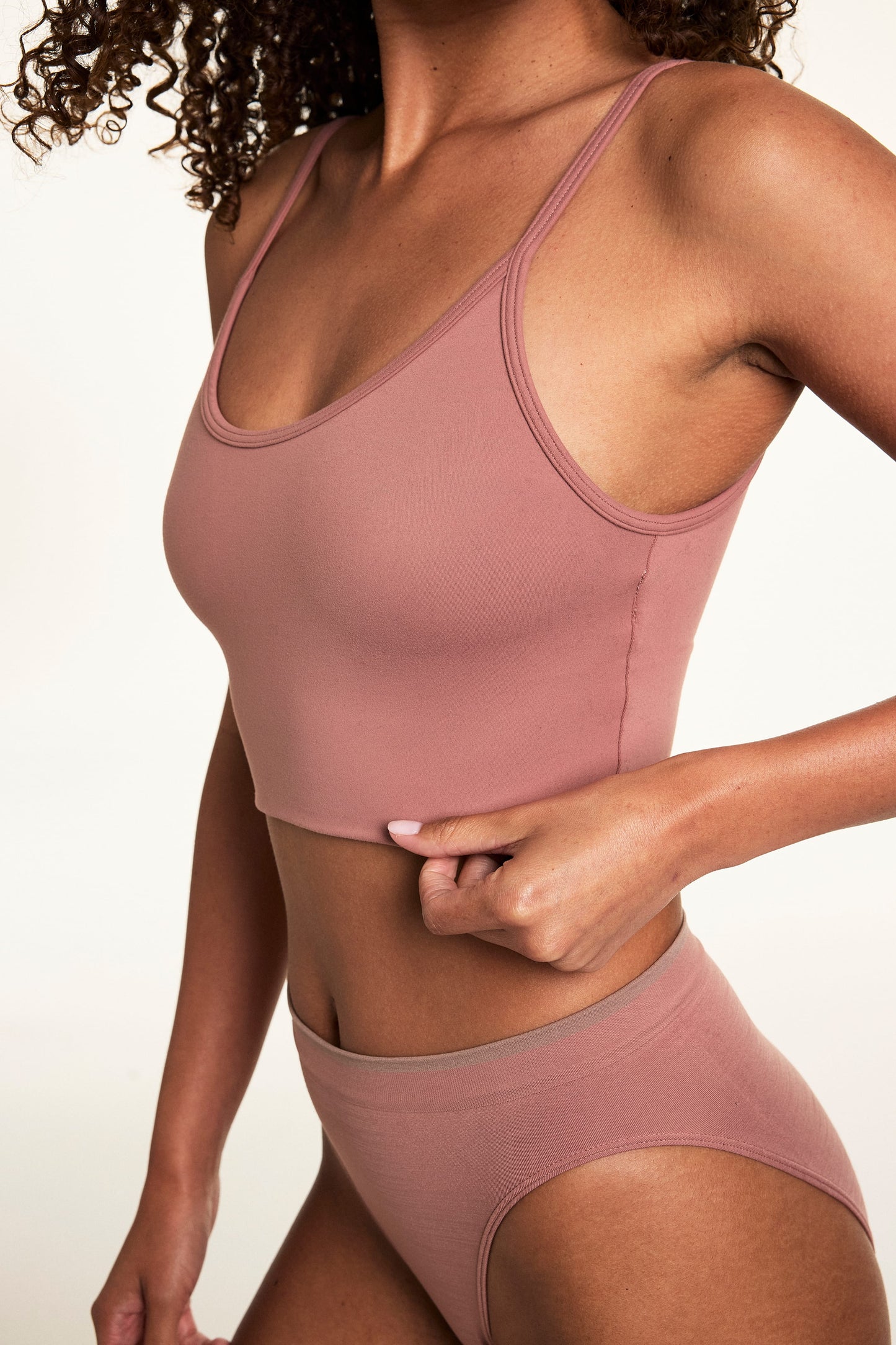 Close-up on a light studio backdrop of Courtney wearing the Whipped Knit Scoop Bralette in Plum with matching underwear. The bralette features a scoop neckline, smooth knit construction, and a longline silhouette.