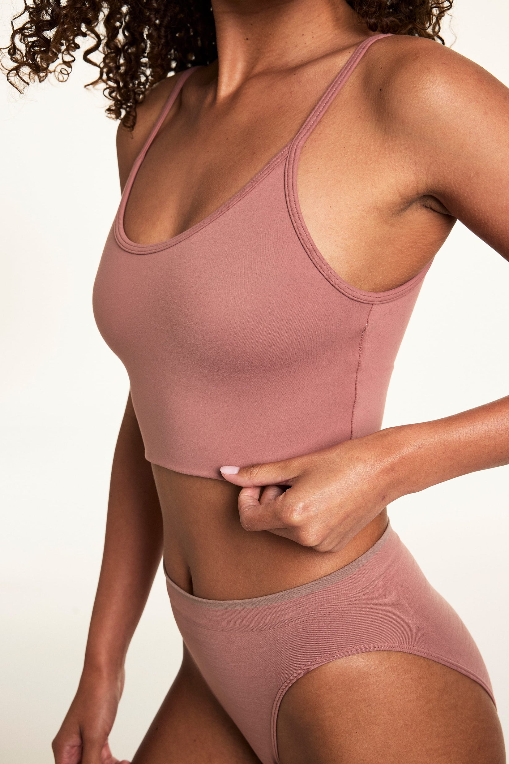 Close-up on a light studio backdrop of Courtney wearing the Whipped Knit Scoop Bralette in Plum with matching underwear. The bralette features a scoop neckline, smooth knit construction, and a longline silhouette.