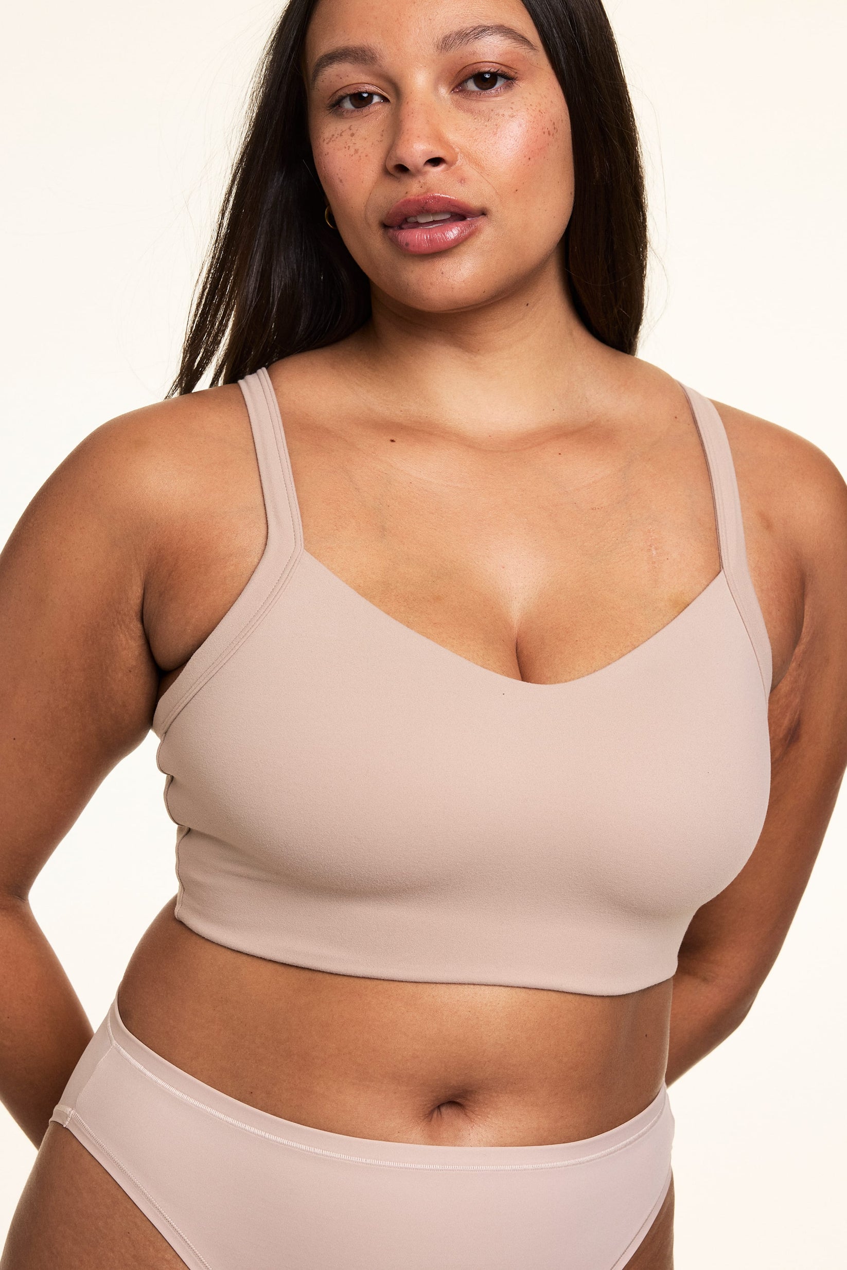 Close-up on a light studio backdrop of Alana wearing the Whipped Knit V-Neck Bralette in Mushroom with matching underwear. The bralette features a V-neck silhouette, wide straps, and soft knit construction. sizing: Alana wears size Large